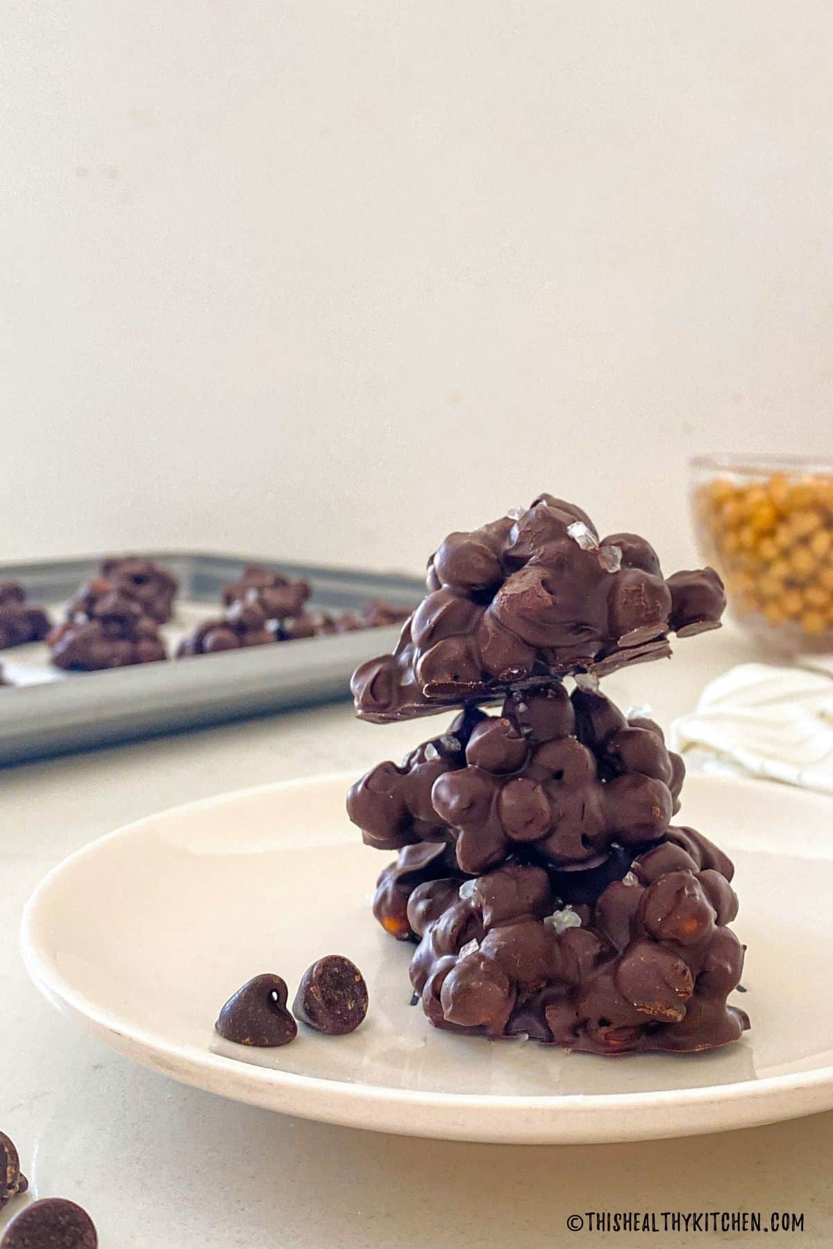 Three chocolate chickpea clusters stacked in a white plate.