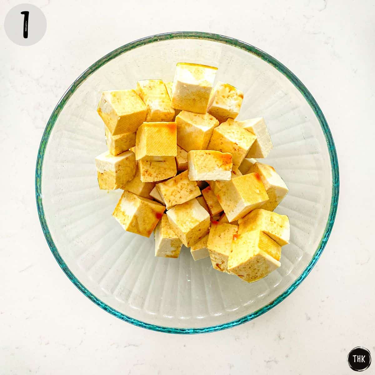 Tofu cubes with soy sauce on top inside mixing bowl.