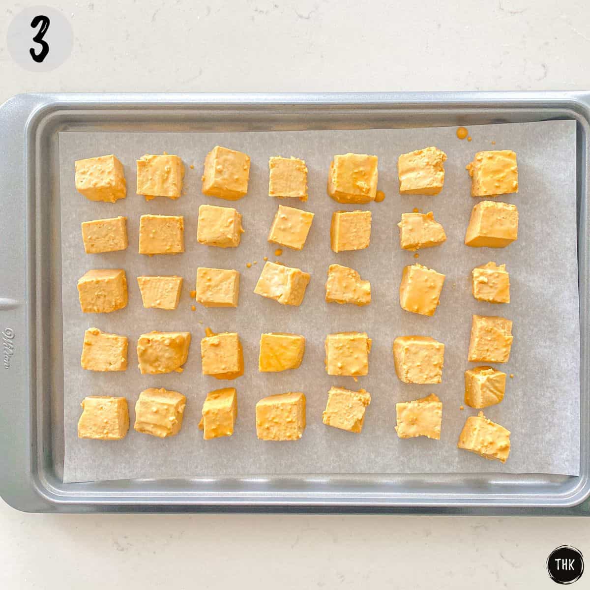 Marinated tofu cubes in a single layer on baking sheet.
