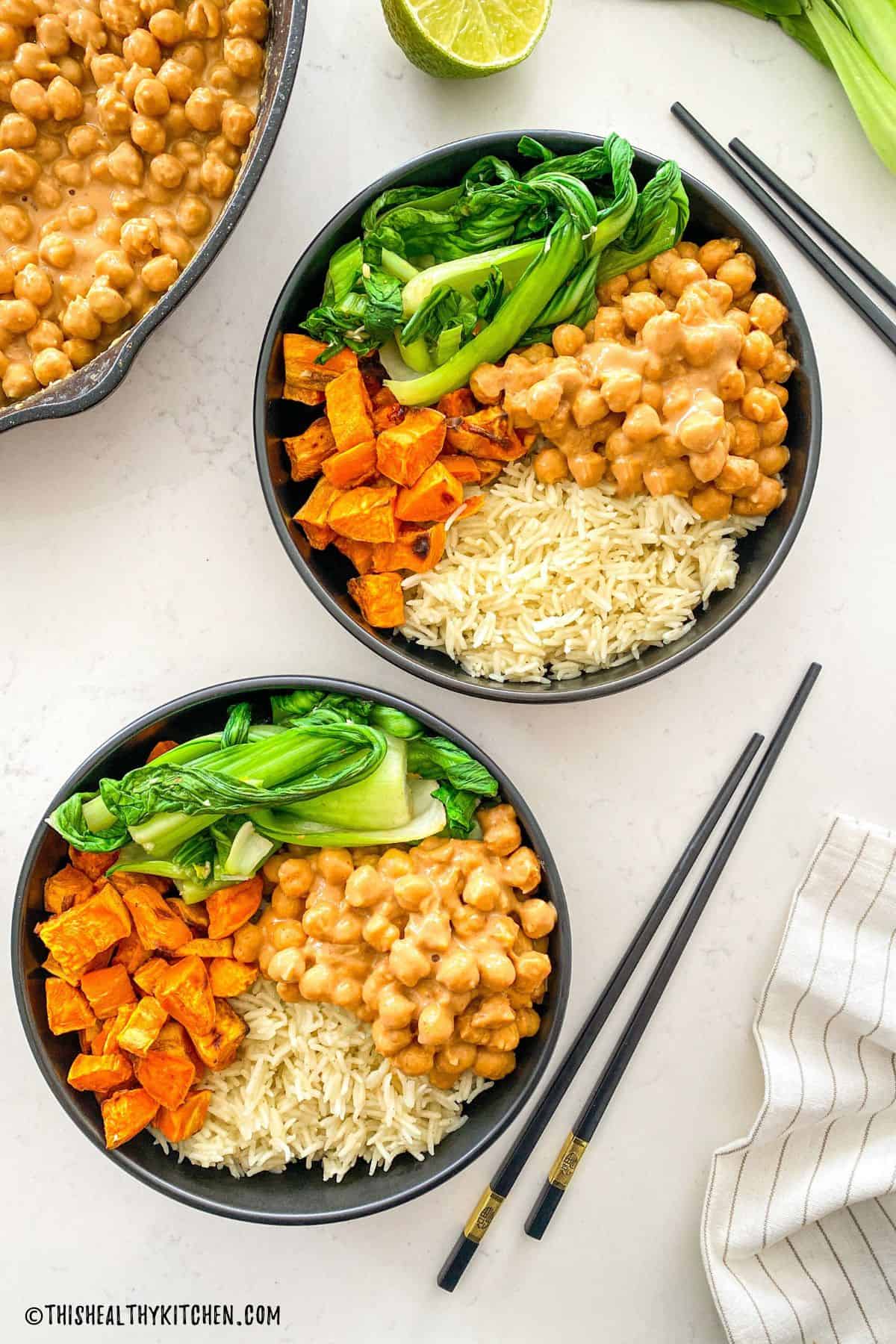 Two Asian buddha bowls with chickpeas, rice, bok choy and sweet potato cubes.