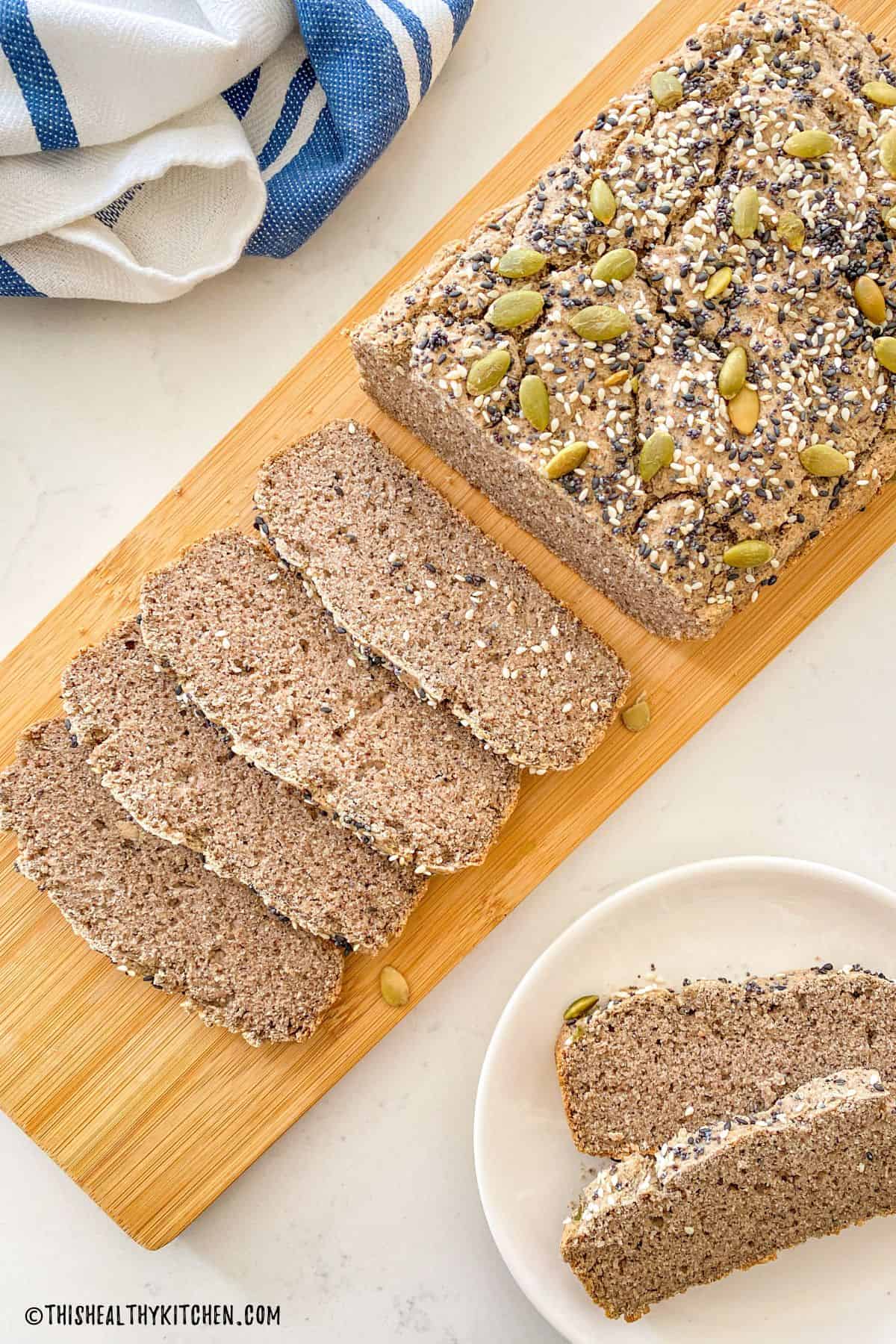 Loaf of bread on cutting board with four slices on their side.