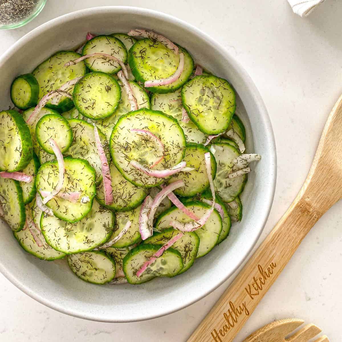 Close-up of cucumber salad with red onion and dill in a serving bowl.
