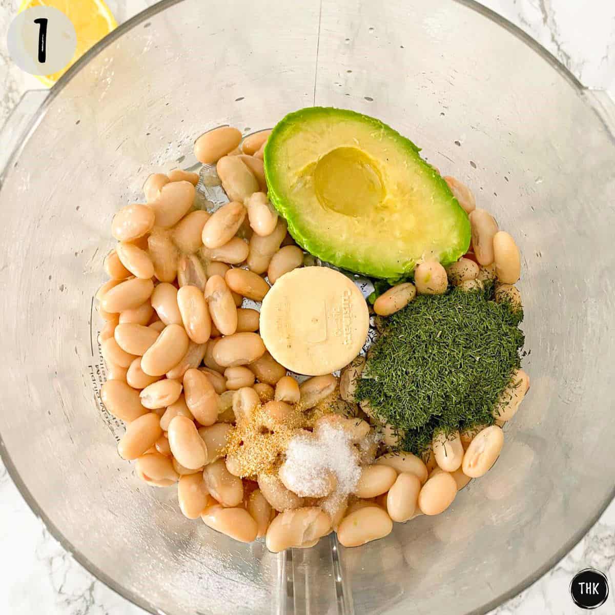 White beans, avocado, and seasoning inside food processor bowl.