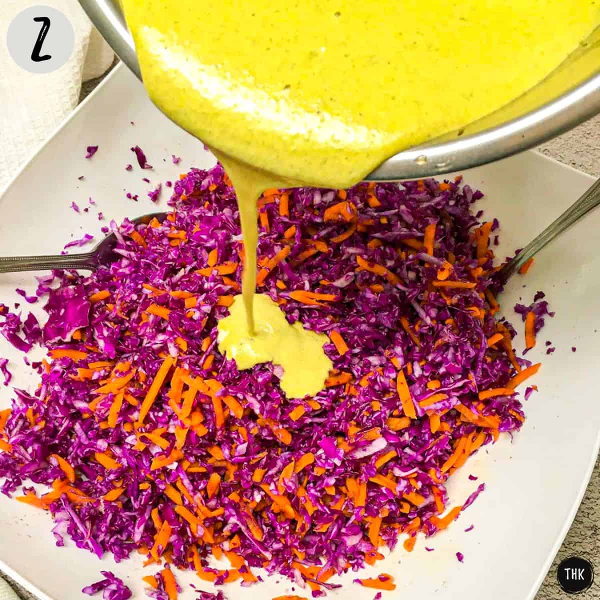Yellow dressing being poured on top of shredded vegetables.