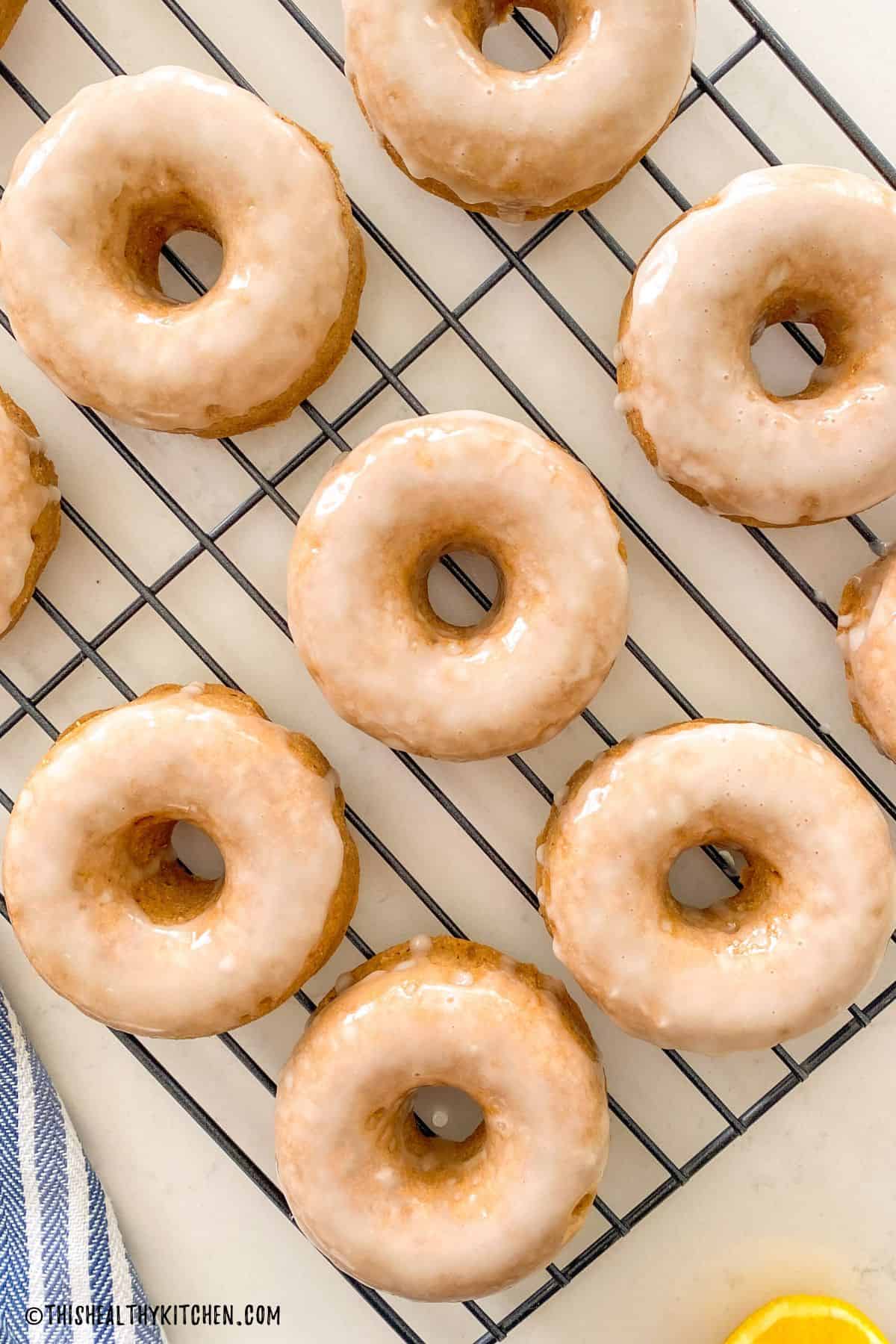 Donuts with glaze on top resting on cooling rack.