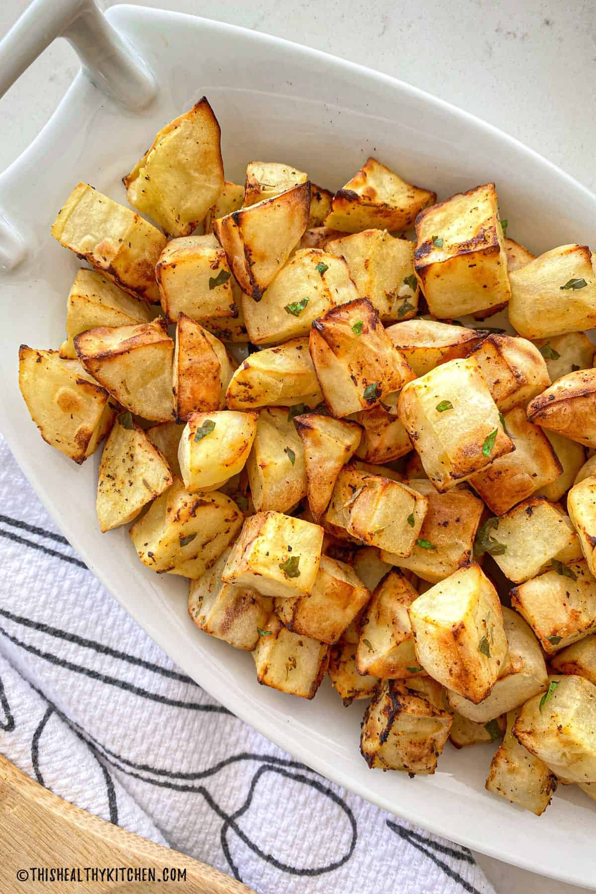 Air fryer diced potatoes inside white serving dish.