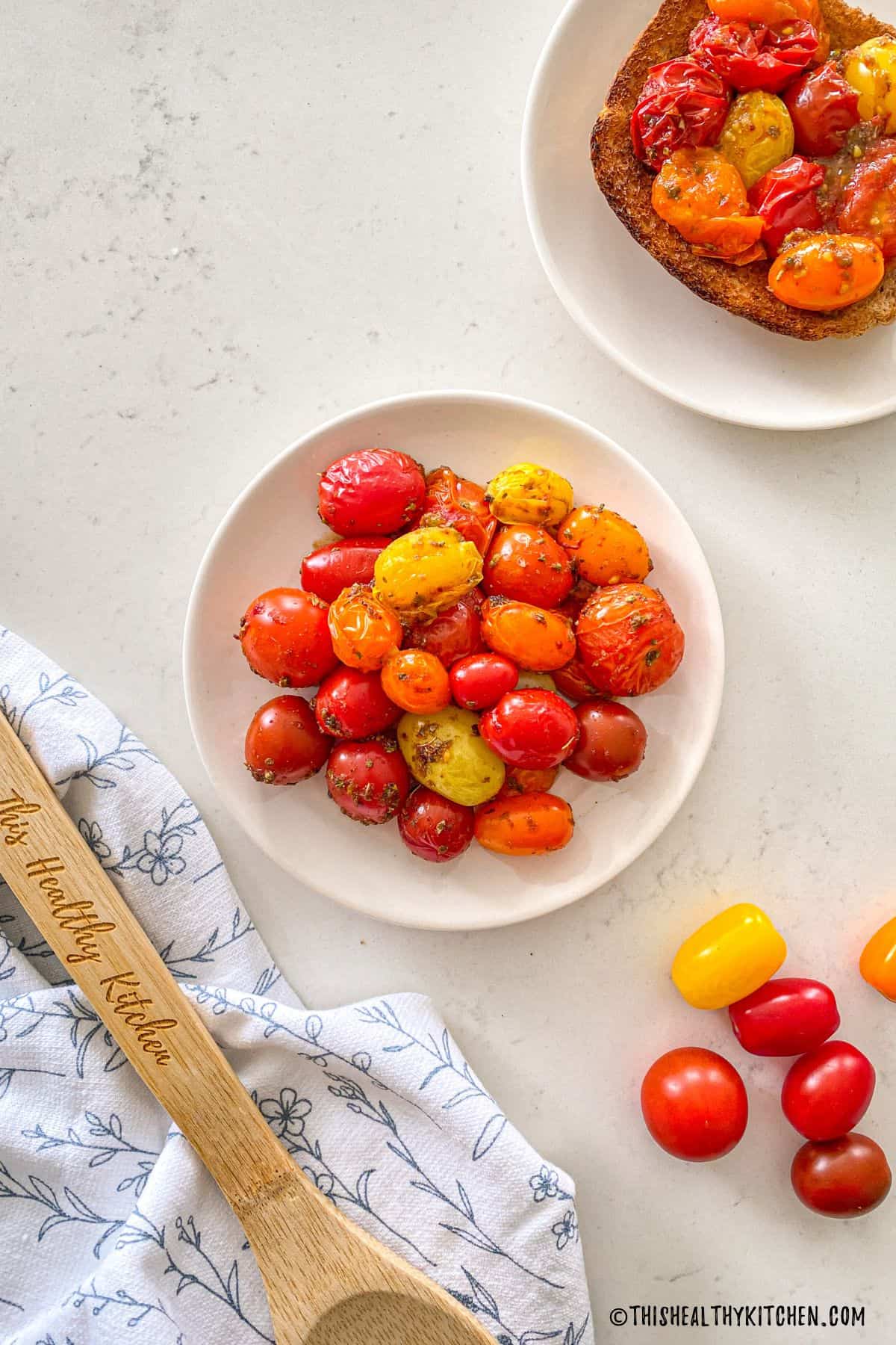 Plate with air fried grape tomatoes and toast in another plate with tomatoes on top.