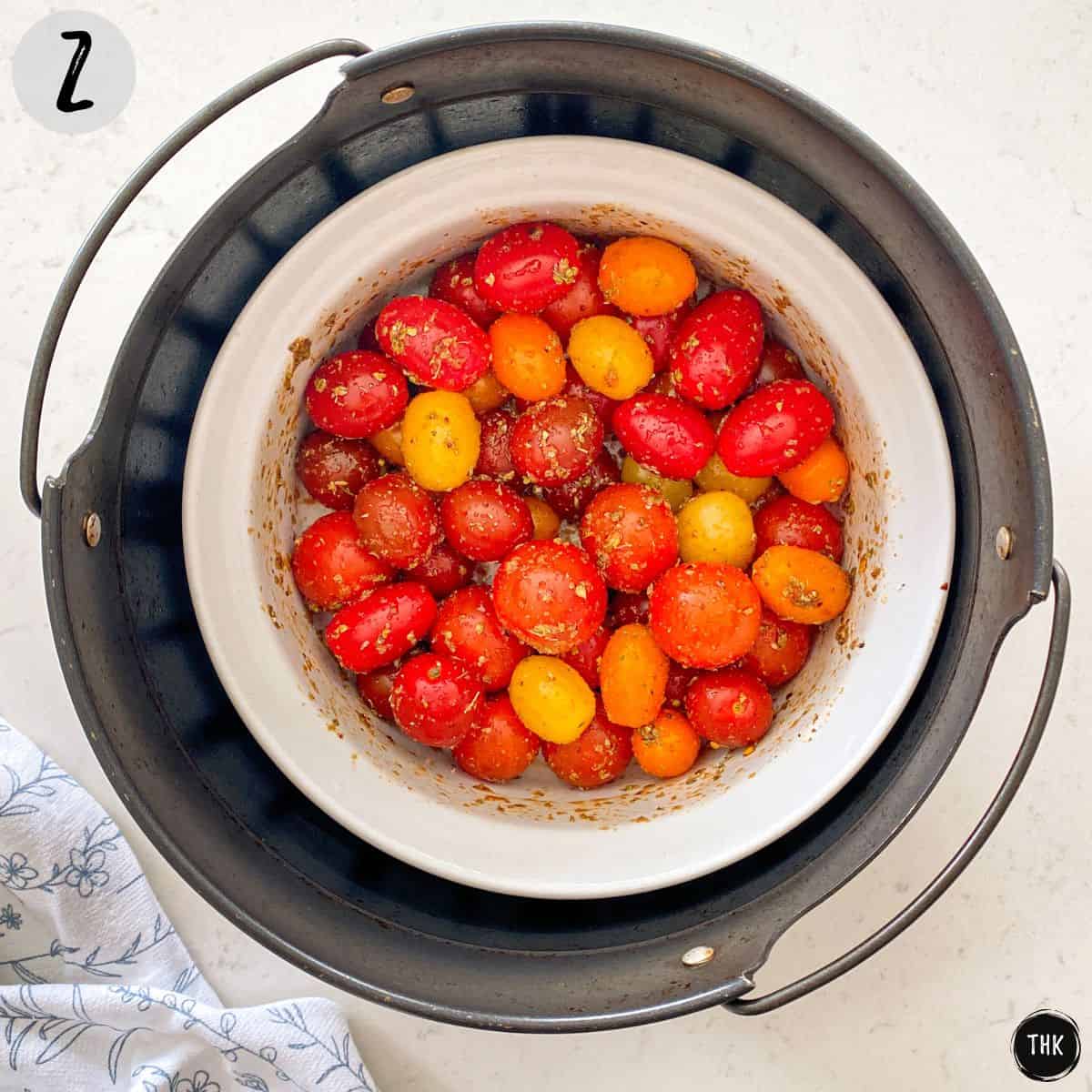 Marinated grape tomatoes inside air fryer basket.
