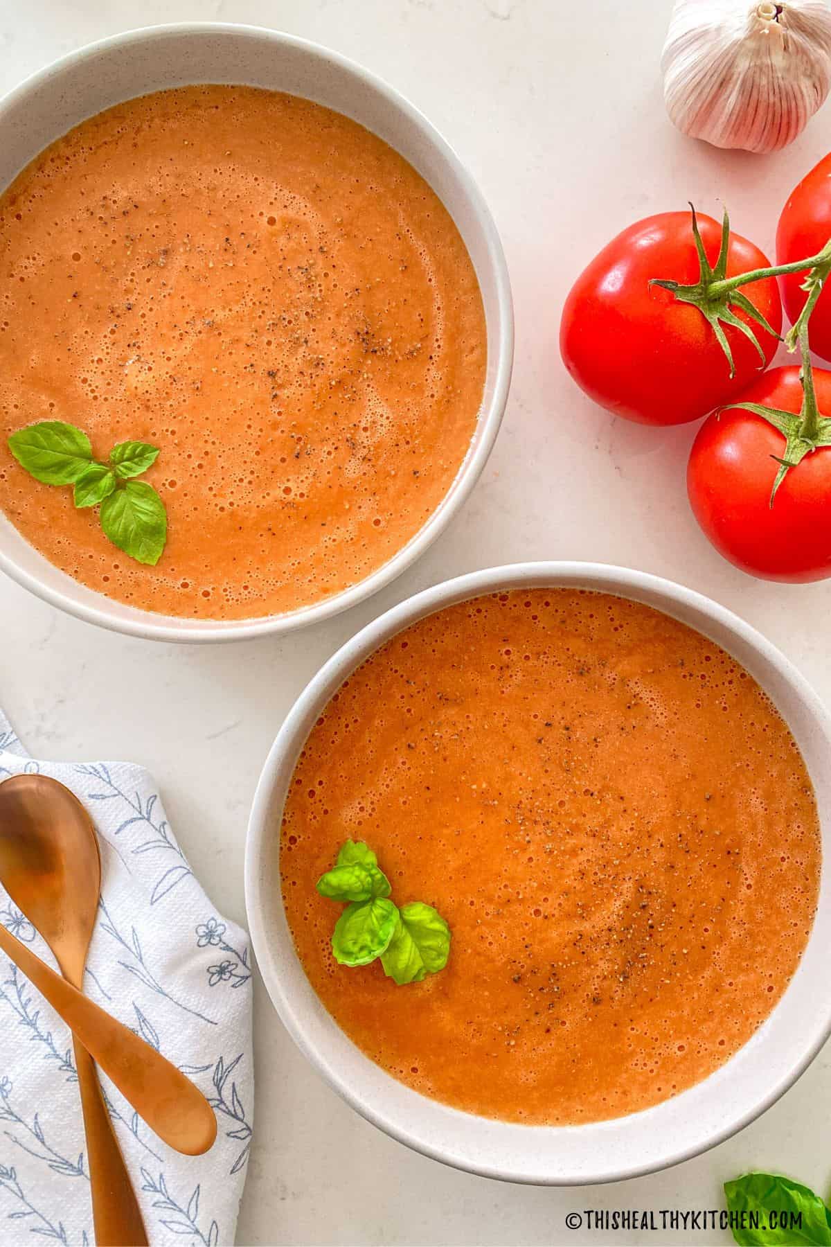 Two bowls of tomato miso soup with fresh basil on top.