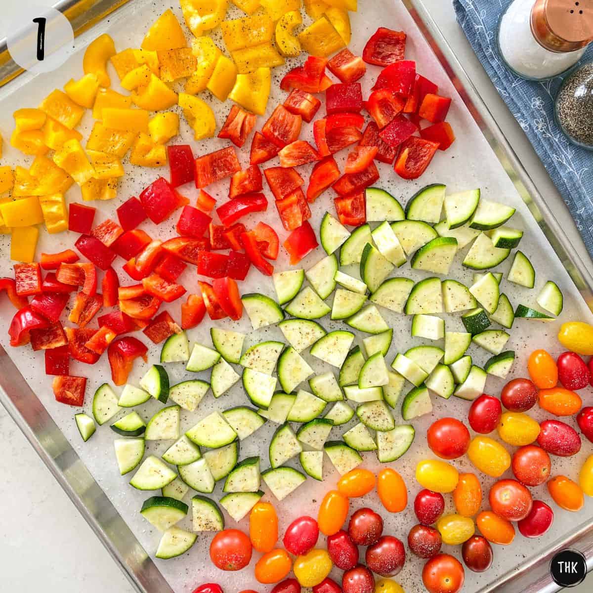 Baking tray with tomatoes, zucchini, and bell peppers inside.