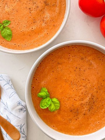 Bowls of tomato miso soup with fresh tomatoes beside them.