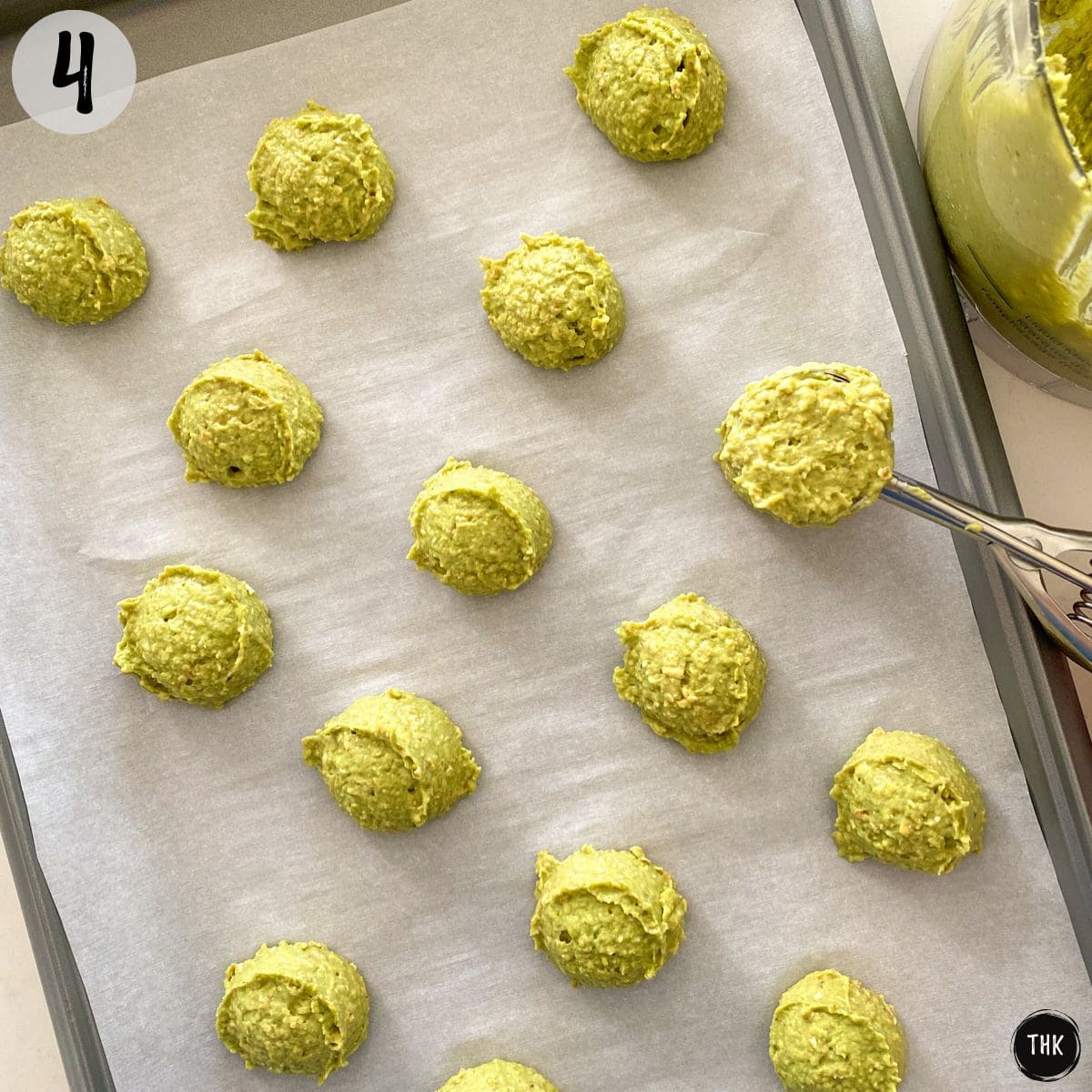 Green cookie dough balls on baking sheet.