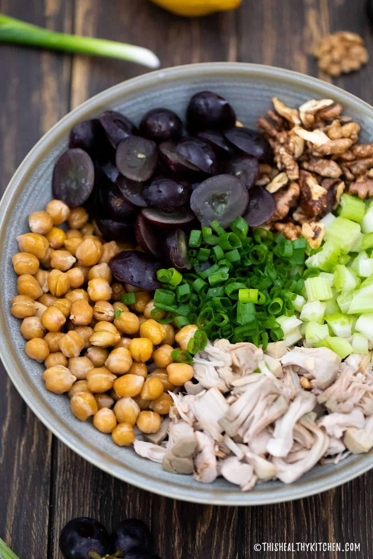 Bowl with shredded jackfruit, chickpeas, grapes, green onion, walnuts, and diced celery.