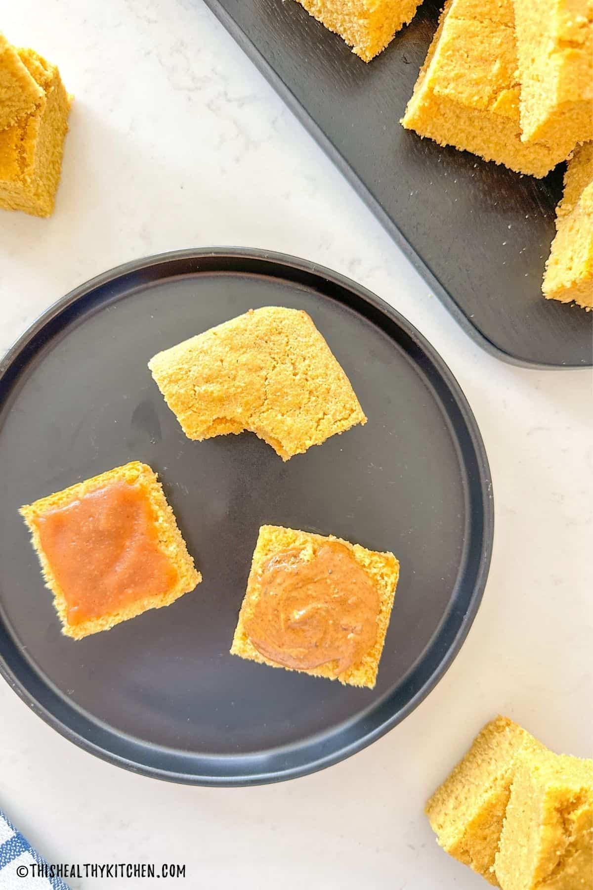 Sliced cornbread with apple butter and nut butter spread on top.