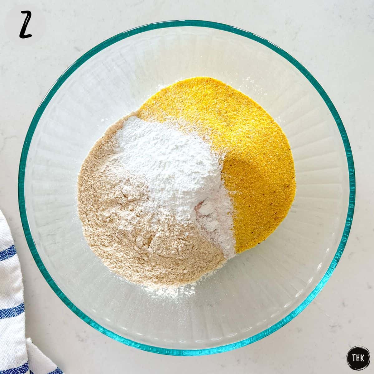 Mixing bowl with flour, baking powder, and cornmeal inside.