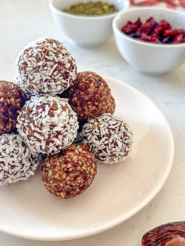 Cranberry energy balls stacked in a white plate.