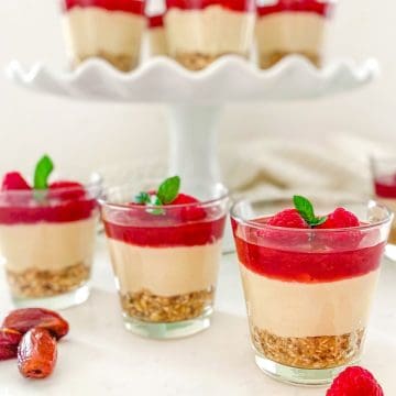 Glass cups with layered vegan cheesecake inside.