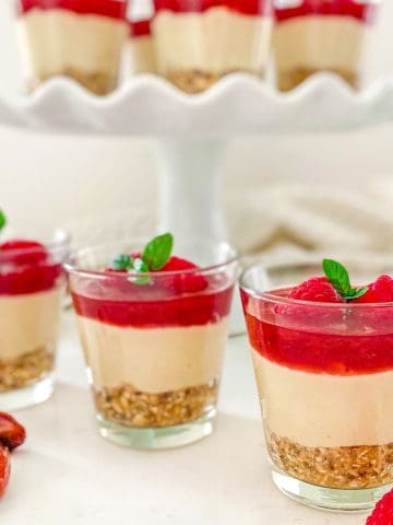 Glass cups with layered vegan cheesecake inside.