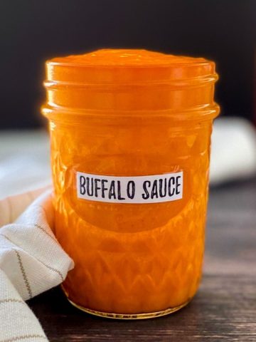 Glass jar with buffalo sauce inside.