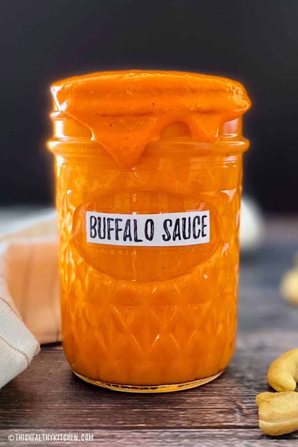 Glass jar with buffalo sauce inside.