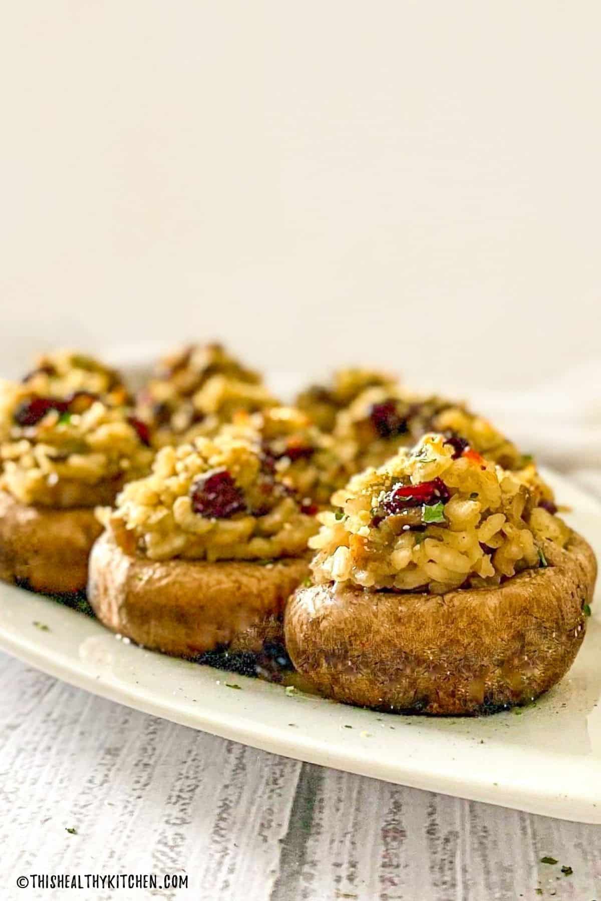 Cranberry risotto stuffed into mushrooms on white tray.