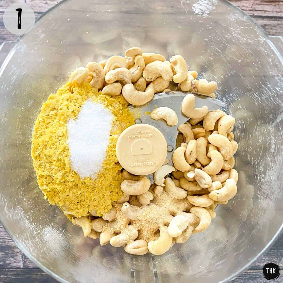 Cashews and seasoning inside food processor bowl.
