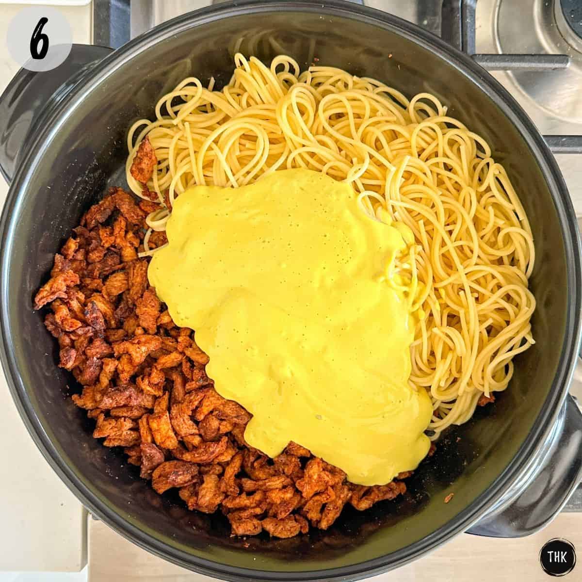 Cooked spaghetti, soy curls and yellow sauce inside large skillet.
