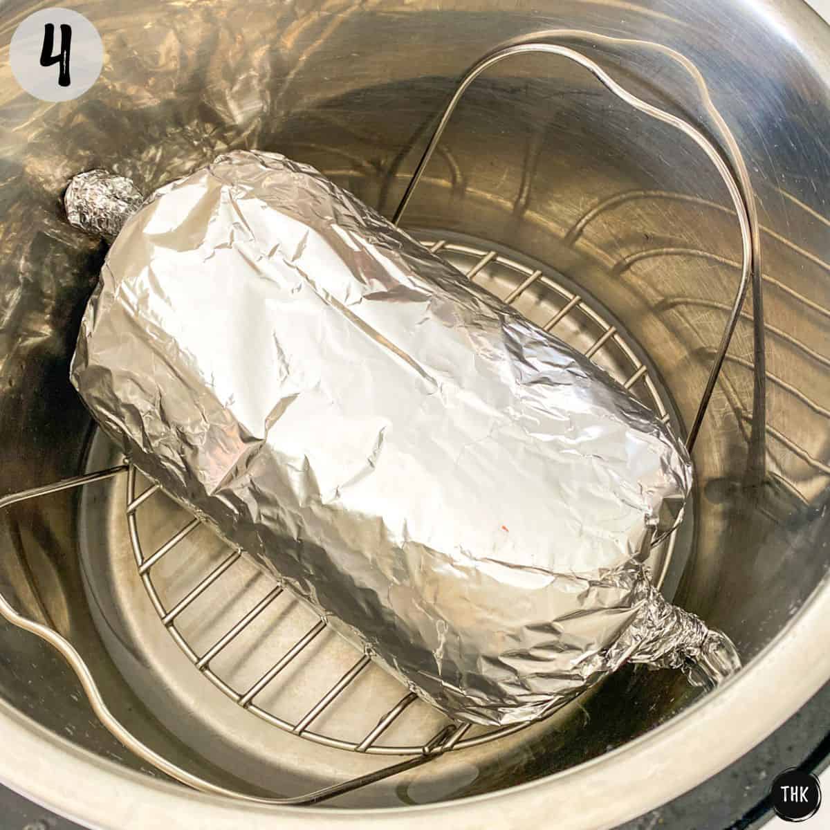 Log shaped roll wrapped in aluminum foil sitting inside Instant Pot.