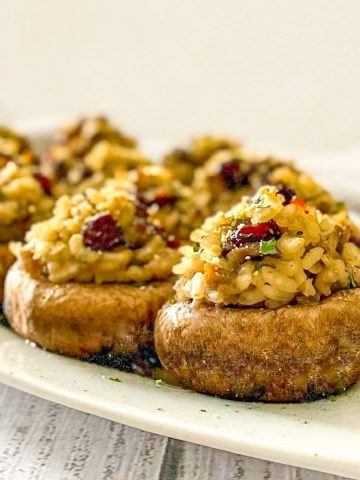 Cranberry risotto stuffed into mushrooms on white tray.