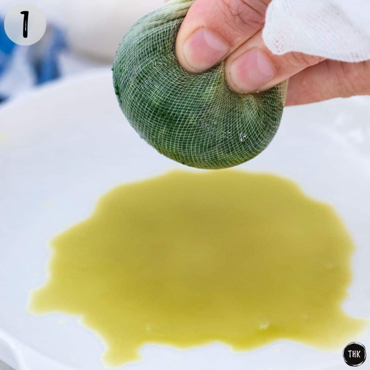 Cooked spinach being squeezed in cheesecloth.