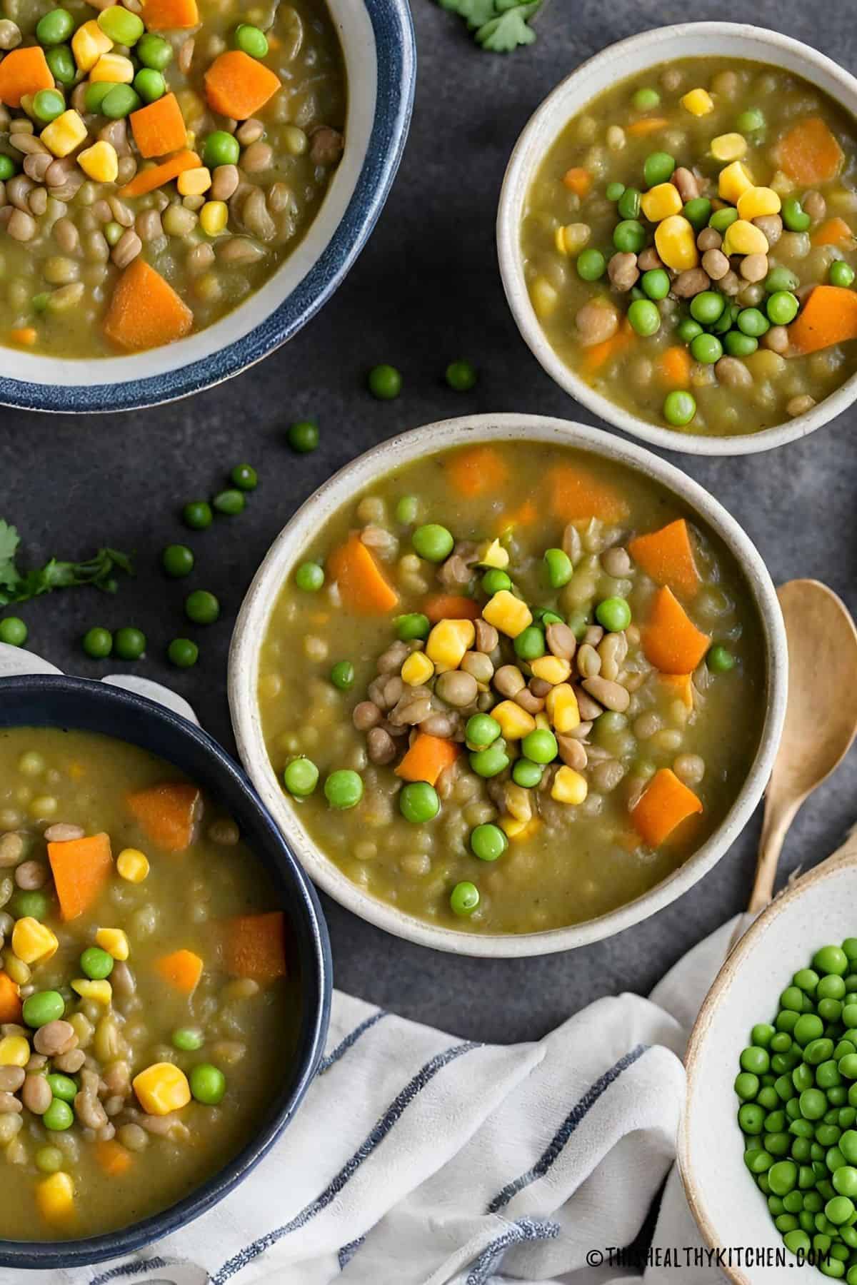 Lentil split pea soup in bowls with green peas in another bowl.