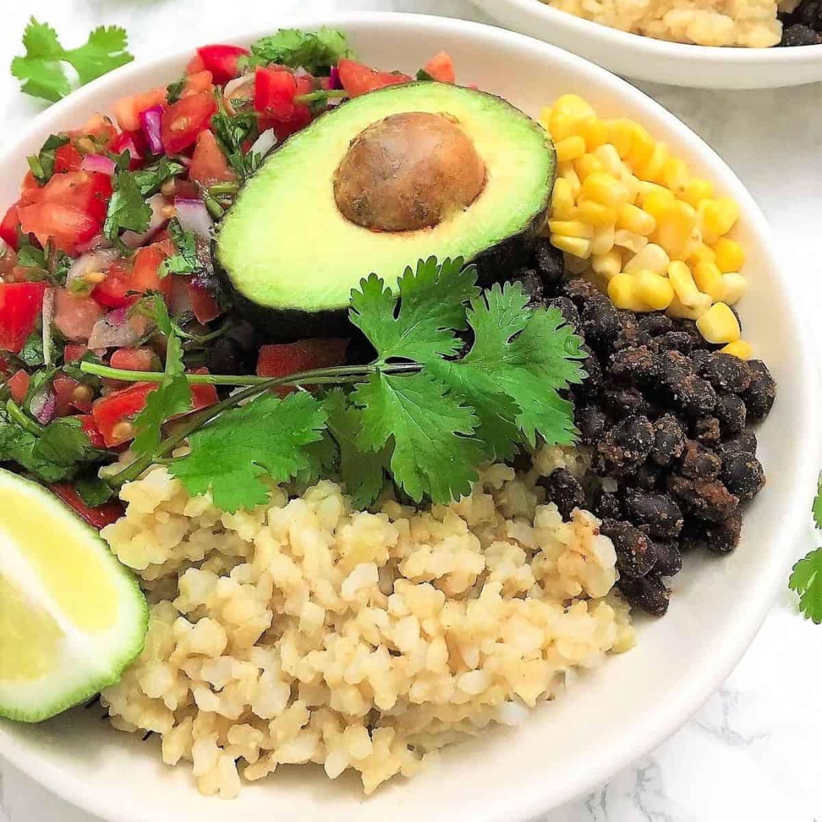 Bowl of rice, black beans, corn, tomato salad and avocado.