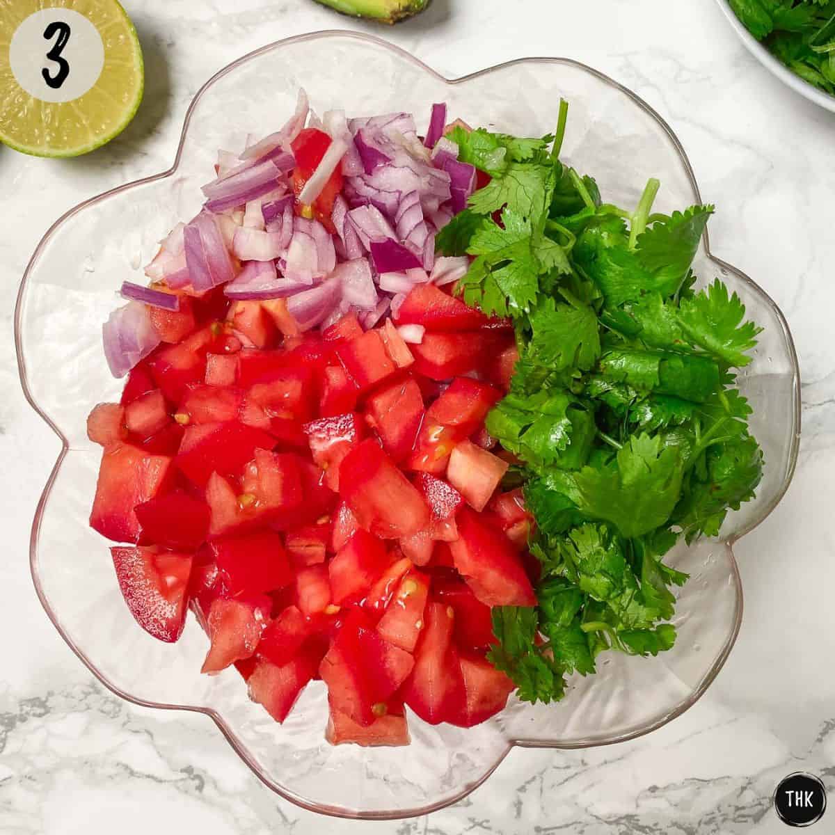 Clear bowl with diced tomato, red onion, and cilantro inside.