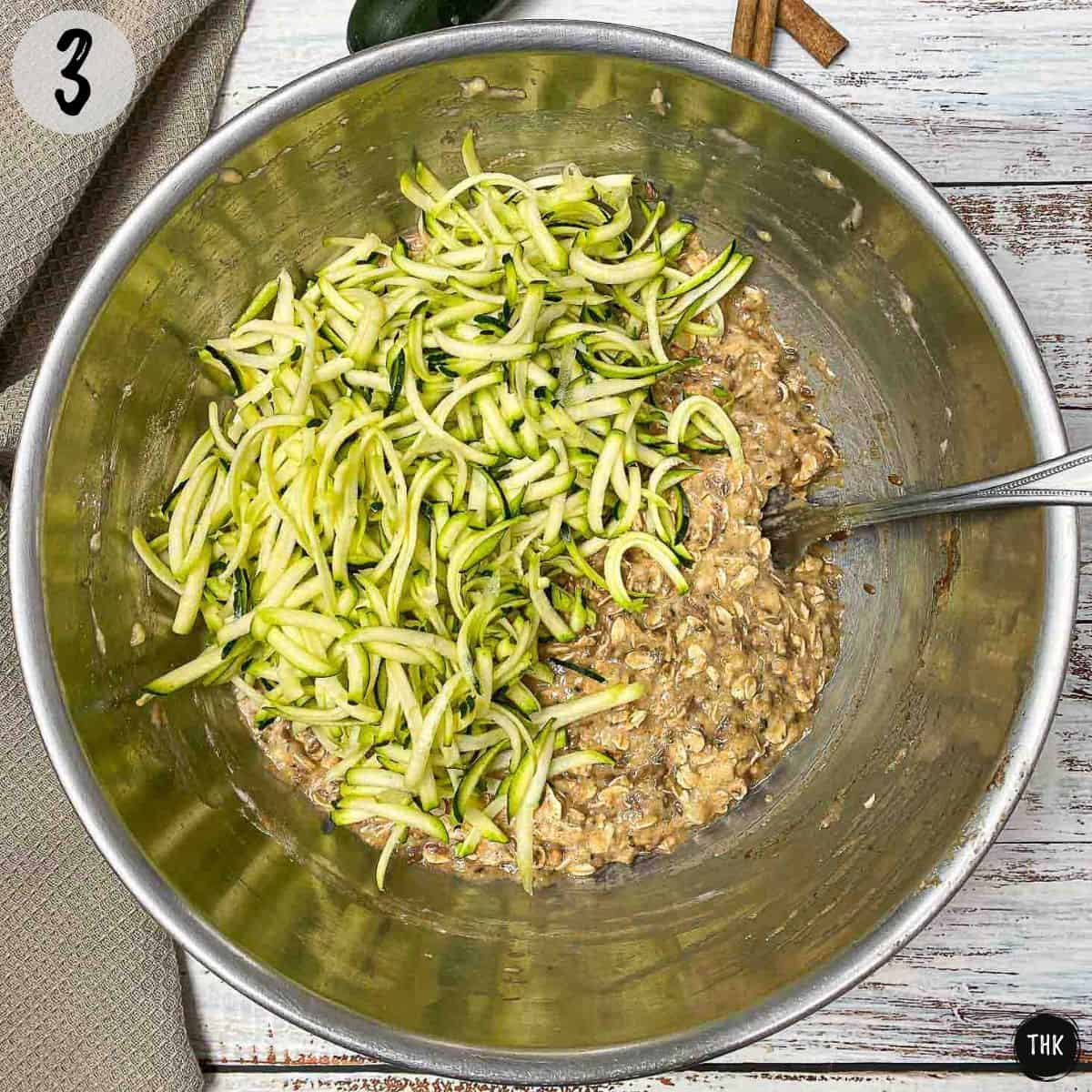 Batter inside large bowl with shredded zucchini on top.