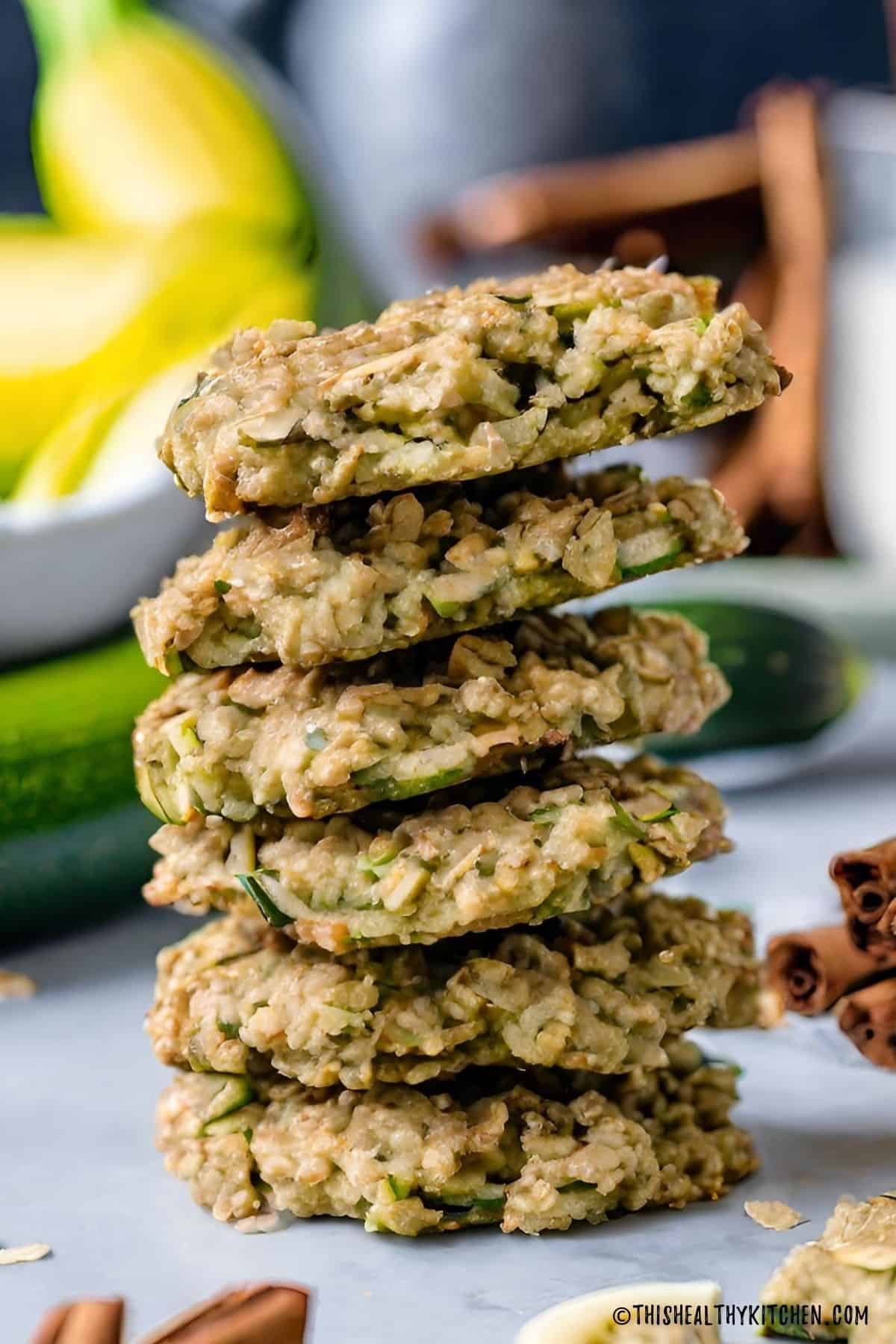 Oatmeal zucchini cookies in a stack with zucchini and cinnamon sticks in the background.