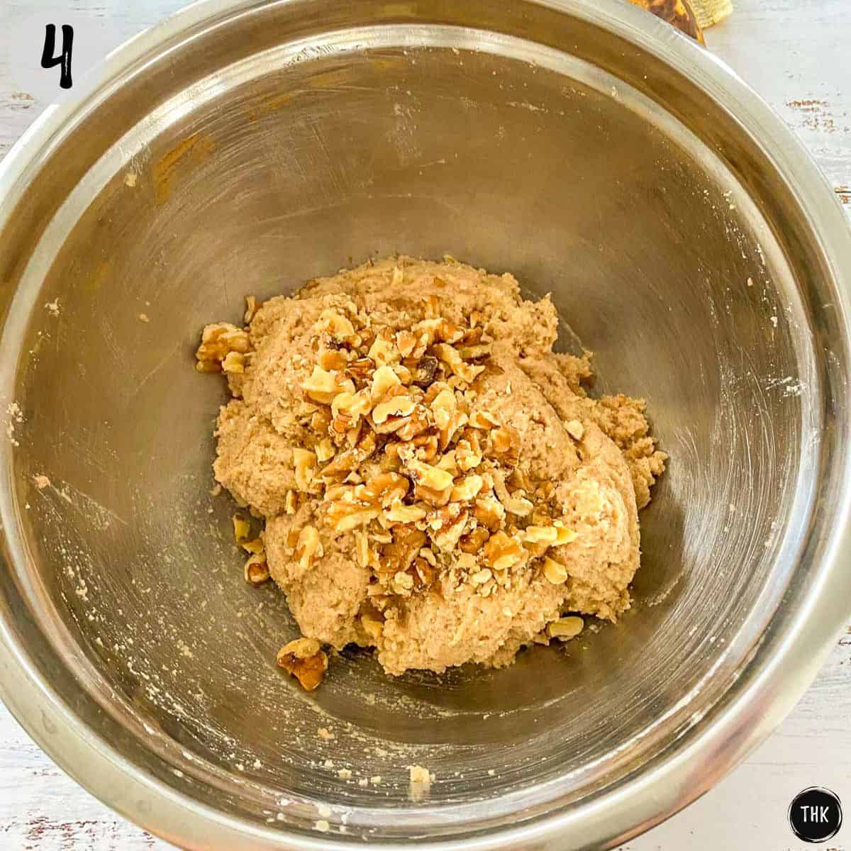 Chopped walnuts on top of muffin batter inside large bowl.