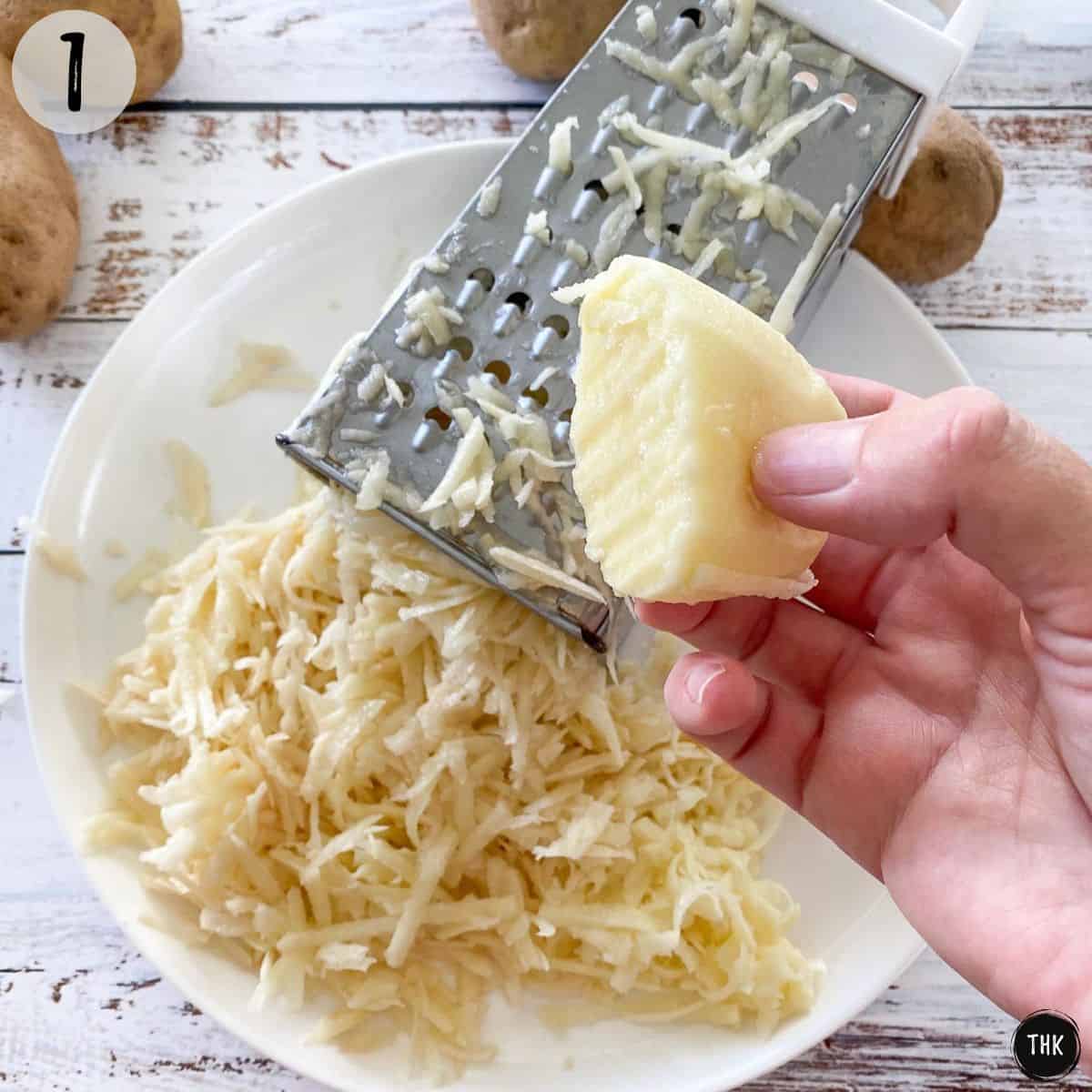 Potatoes being grated using a shredder into a white plate.