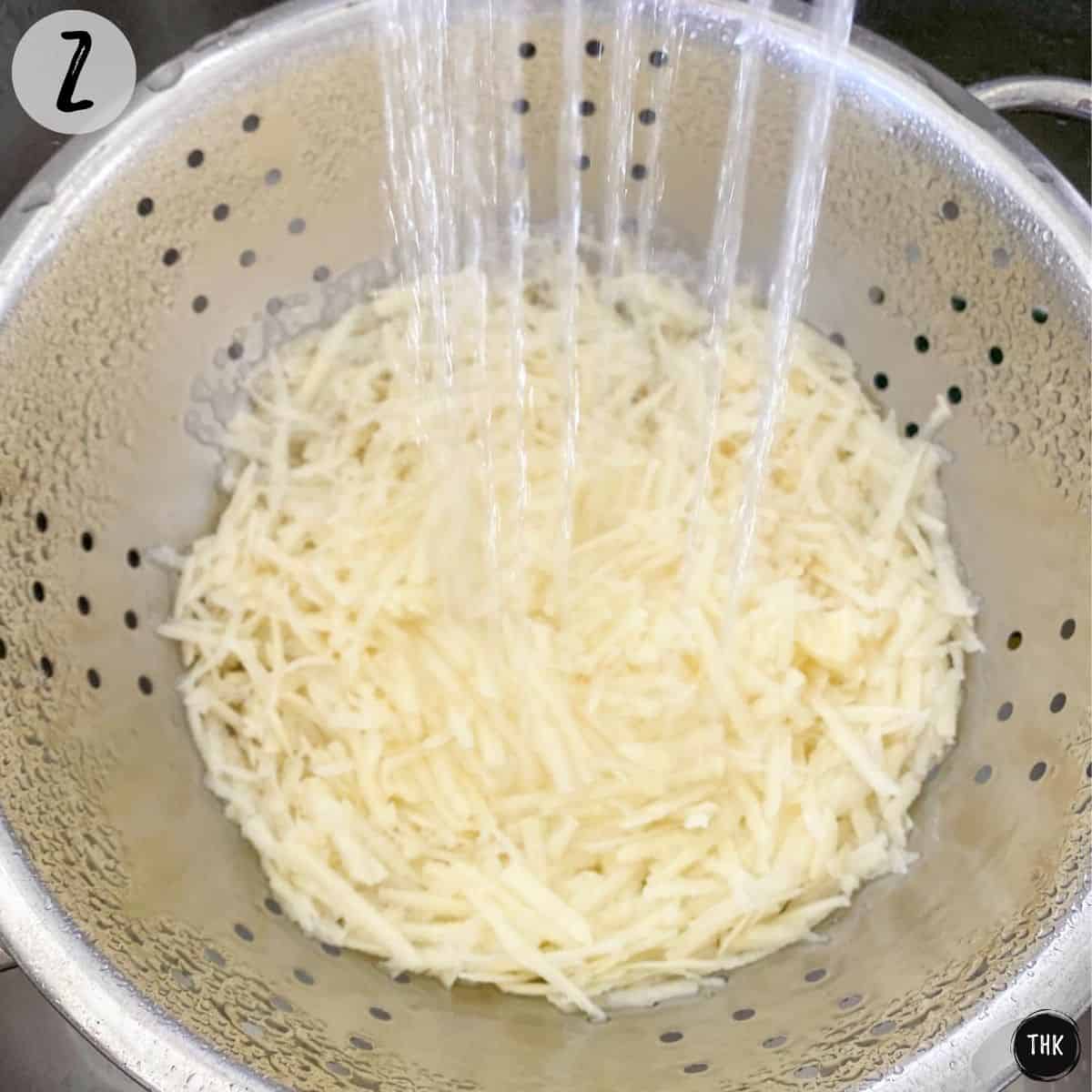 Shredded potatoes being rinsed inside colander.