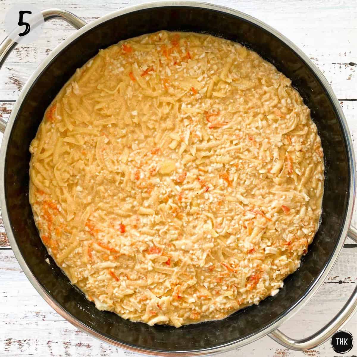 Shredded veggies and orange sauce inside large casserole pan.