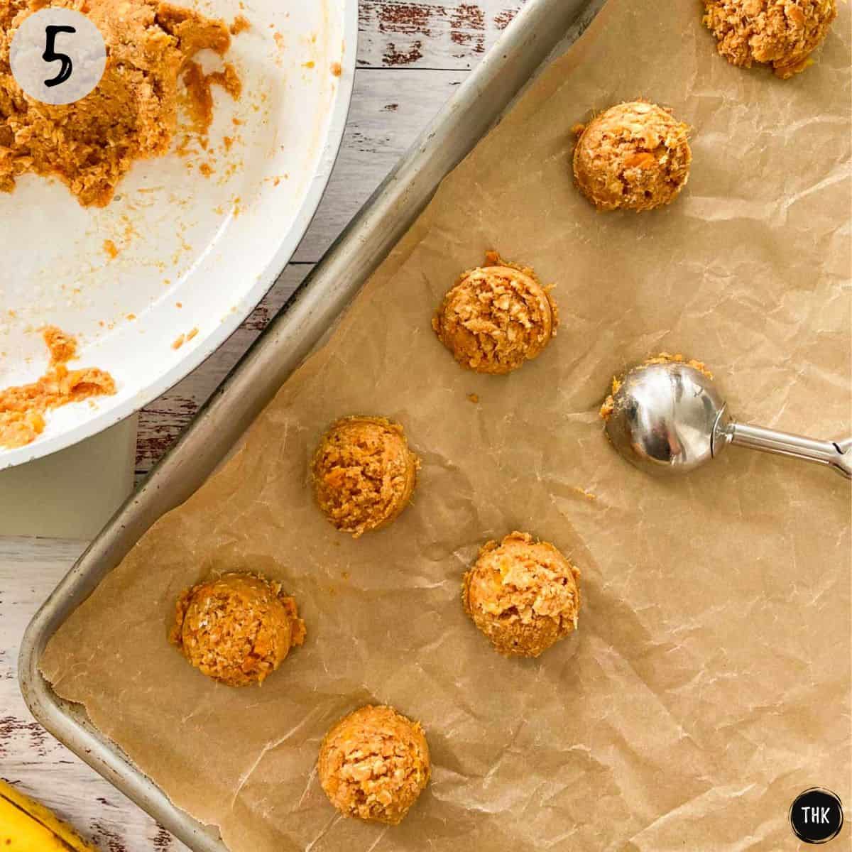 Cookie scoop placing balls of cookie dough on baking sheet.