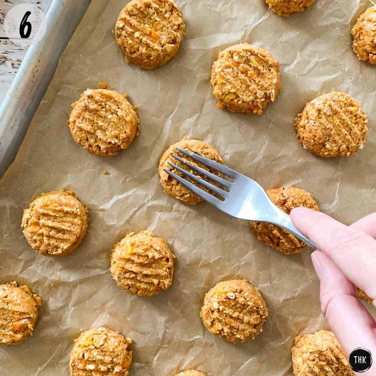 Fork pressing down cookies on baking sheet.