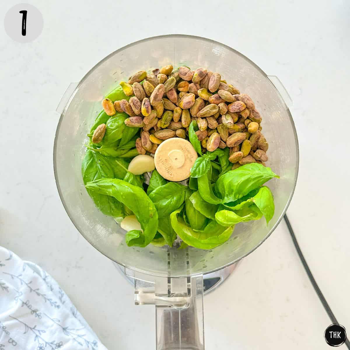 Food processor with basil, garlic, pistachios and lime juice.