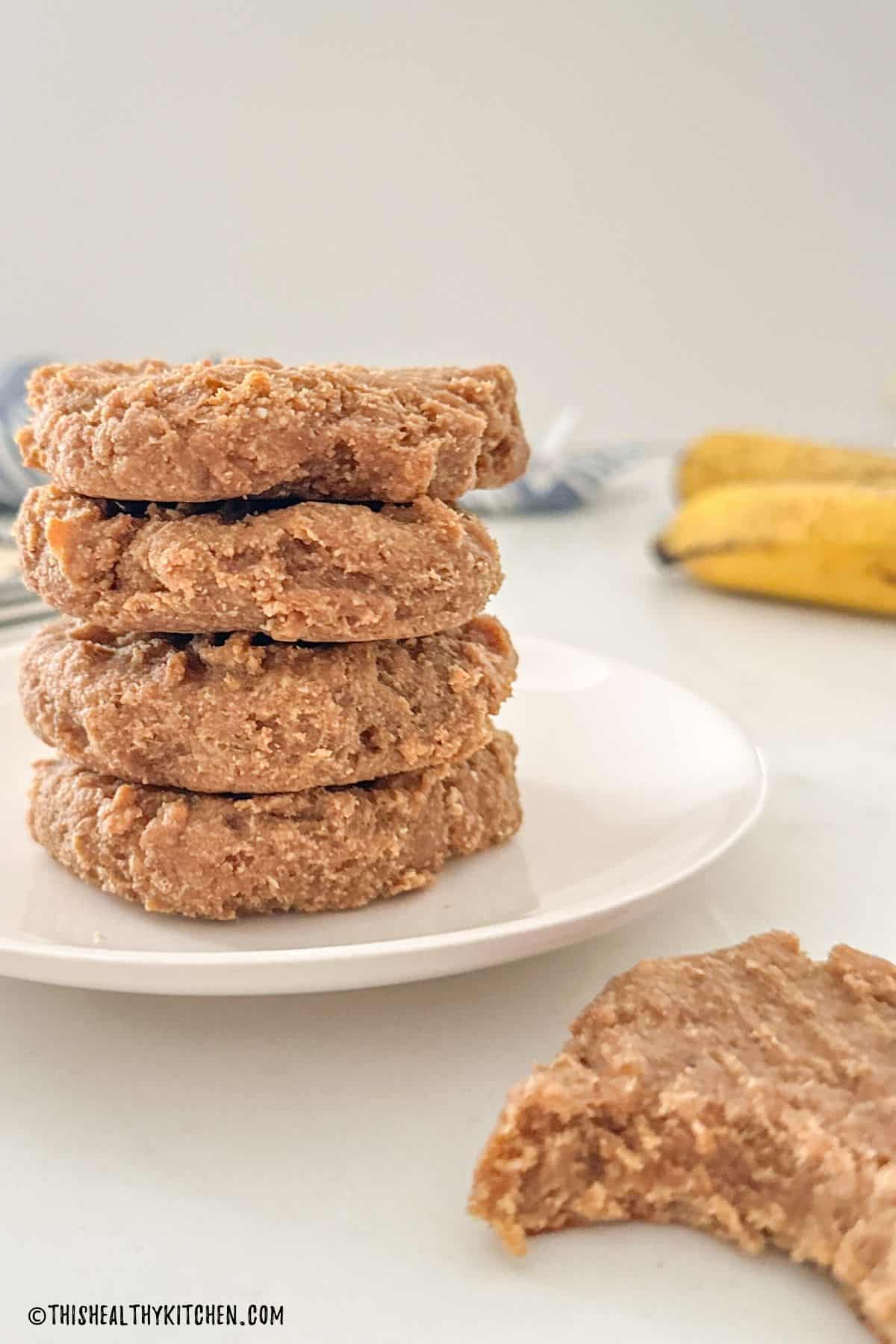 Cookies stacked on plate with 1 cookie in front of the stack with bite taken out.