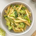 Bowl of pasta with asparagus and broccoli and vegan parmesan cheese on top.