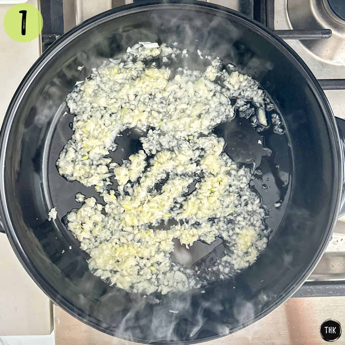 Minced onion and garlic being sautéed in deep skillet.