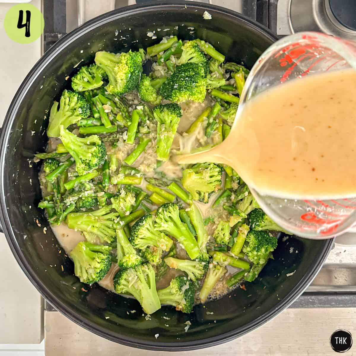 Creamy sauce being poured into pan with sauteed veggies.