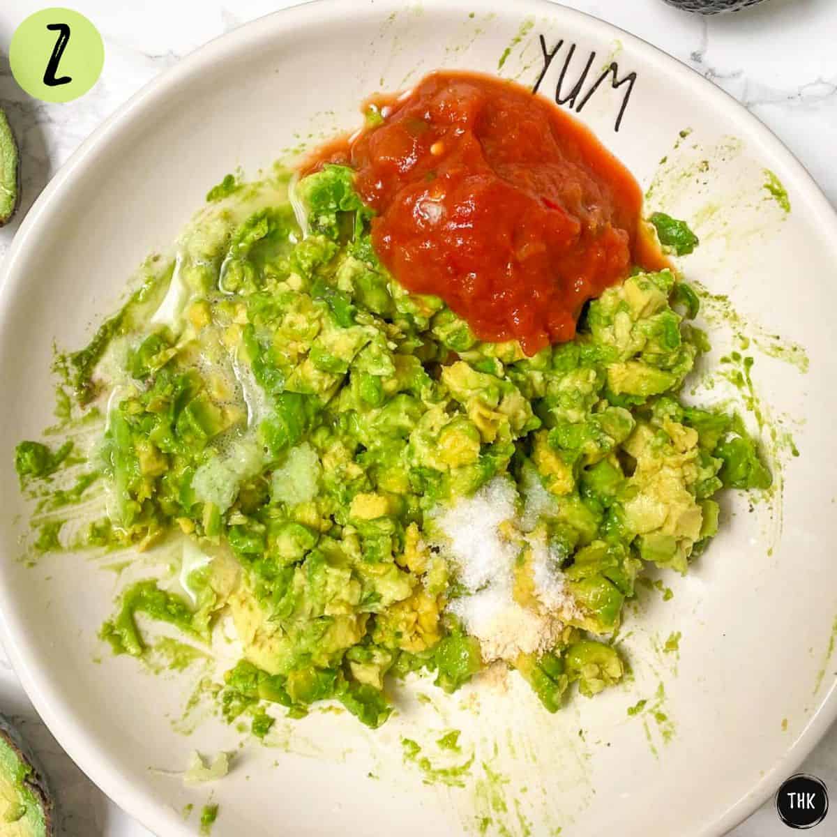 Mashed avocado, lime juice, salt, and salsa in white bowl.