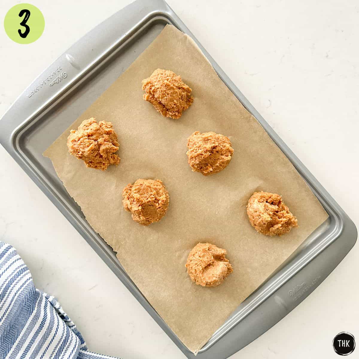 Cookie dough balls on baking sheet lined with parchment paper.