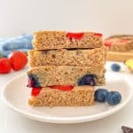 Side view of stack of 4 square slices of sheet pan pancakes studded with fruit.