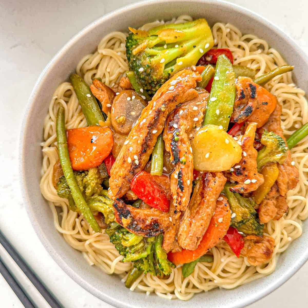 Soy curl stir fry over rice noodles in bowl.